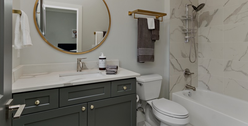 Bathroom with green vanity and marble-look tile after sealing