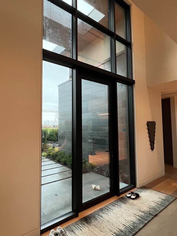 Two-storey black-framed entry glazing sealed with black silicone