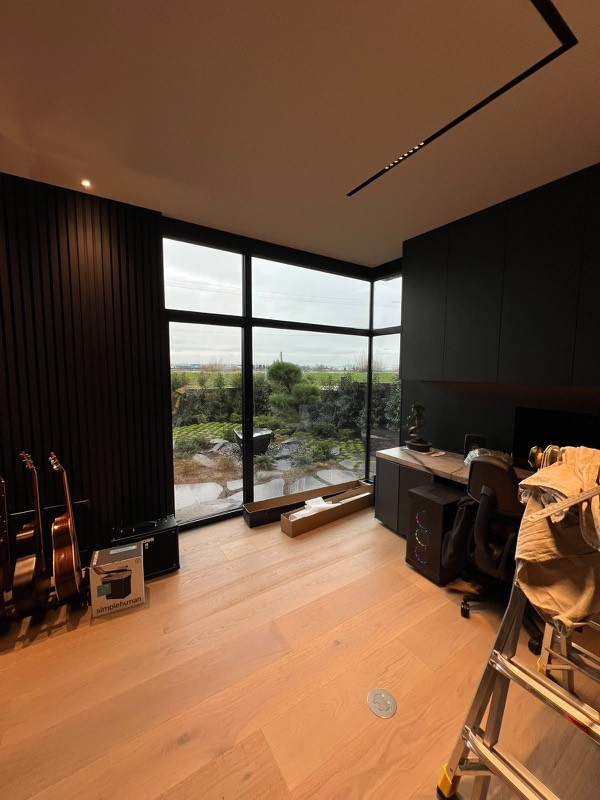 Black-framed corner windows in a custom home office, sealed in black silicone