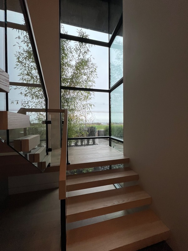 Two-storey black-framed stair window sealed in black silicone