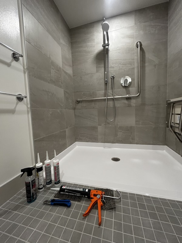 Accessible shower base with grab bars and fold-down seat