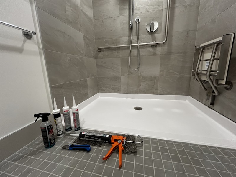 Accessible roll-in shower being sealed by Nubrix, tools on site