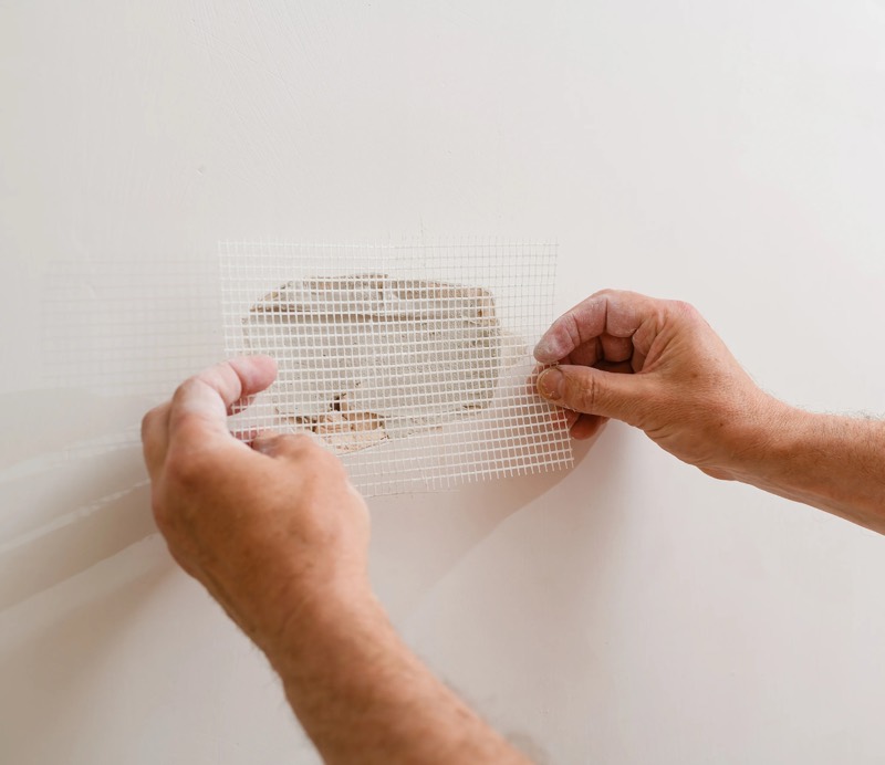 Drywall patch mesh being applied over a damaged wall