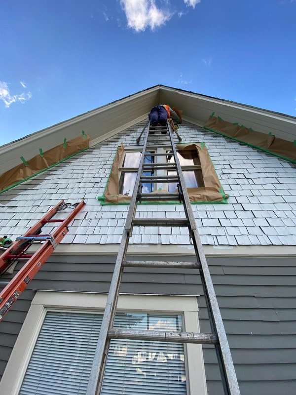 Working on a home’s upper gable from a ladder