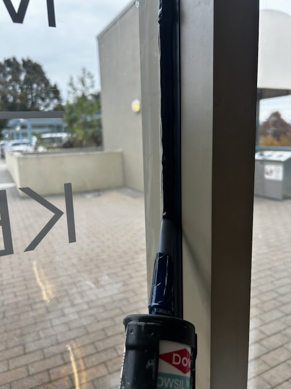 Black silicone being applied along a storefront glass-to-frame joint